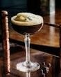 Classic espresso martini cocktail on a rustic wooden bar in a London pub.